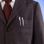 Gros plan sur une veste de costume sombre, évoquant l'idée d'un dispositif d'espionnage discret comme une bouton caméra.