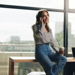 Woman, coffee and phone call with discussion in office for article info, source interview and chat. Publishing agency, journalist and speaking to contact for appointment schedule and story feedback